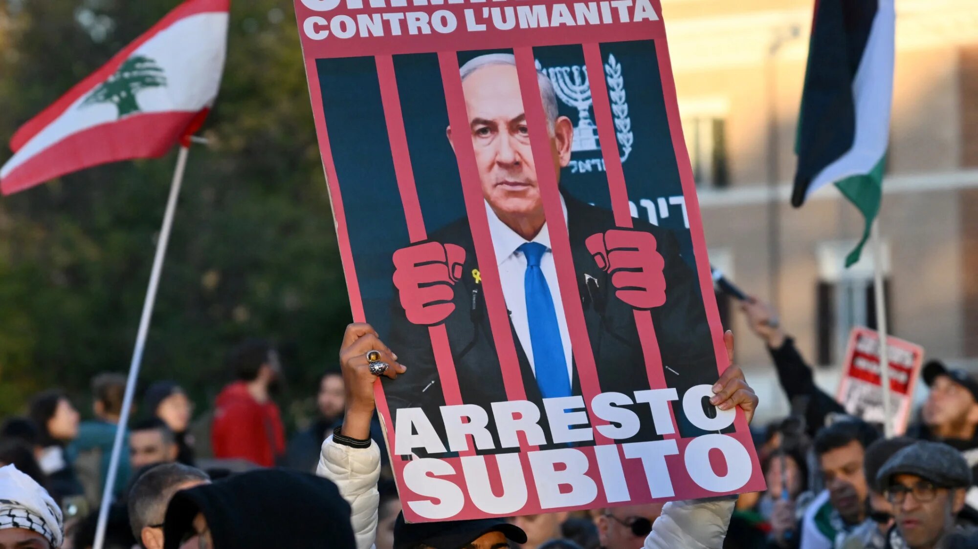 A demonstrator holds up a placard depicting Israeli Prime Minister Benjamin Netanyahu behind bars during a rally in support of Palestinians in Rome on 30 November 2024 (AFP/Alberto Pizzoli)