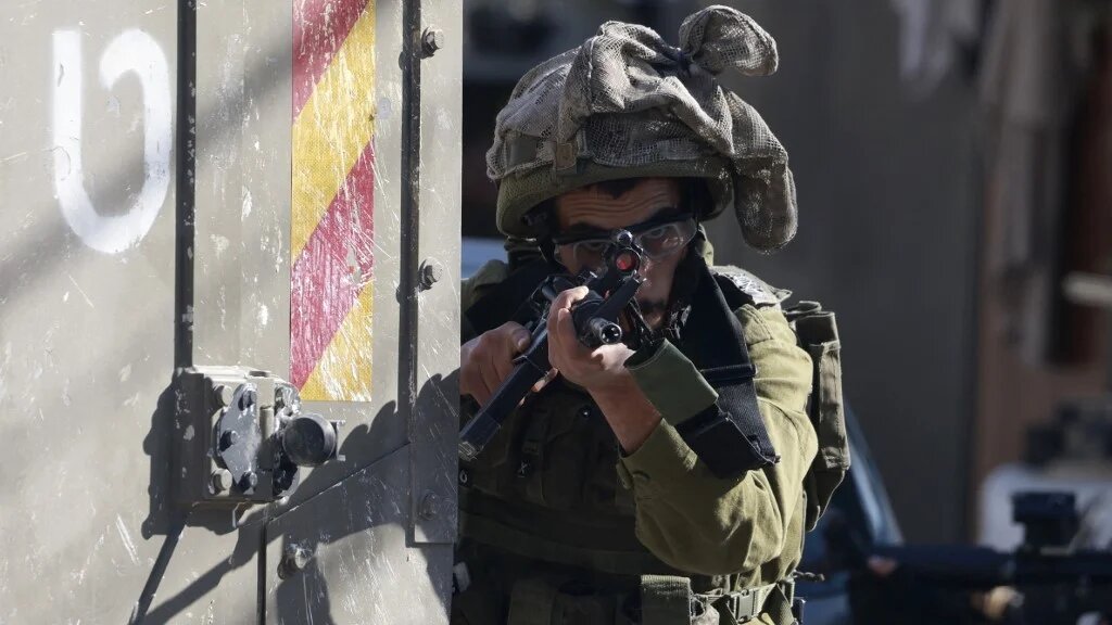 An Israeli soldier takes aim outside the Tubas Turkish Governmental Hospital in Tubas in the occupied West Bank on December 3, 2024