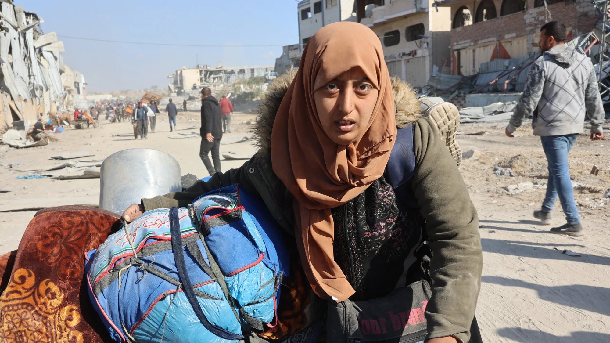 A Palestinian woman, displaced from Beit Lahia, arrives with her belongings in Jabalia in the northern Gaza Strip on 4 December 2024 (AFP/Omar al-Qattar)