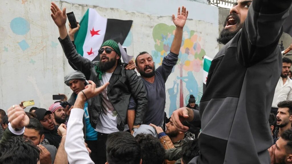 Syrians wave the opposition flag in Arbil, the capital of Iraq's northern autonomous Kurdish region, on December 8, 2024, as they celebrate the capture of the capital Damascus by rebel forces (Safin Hamid/ AFP)