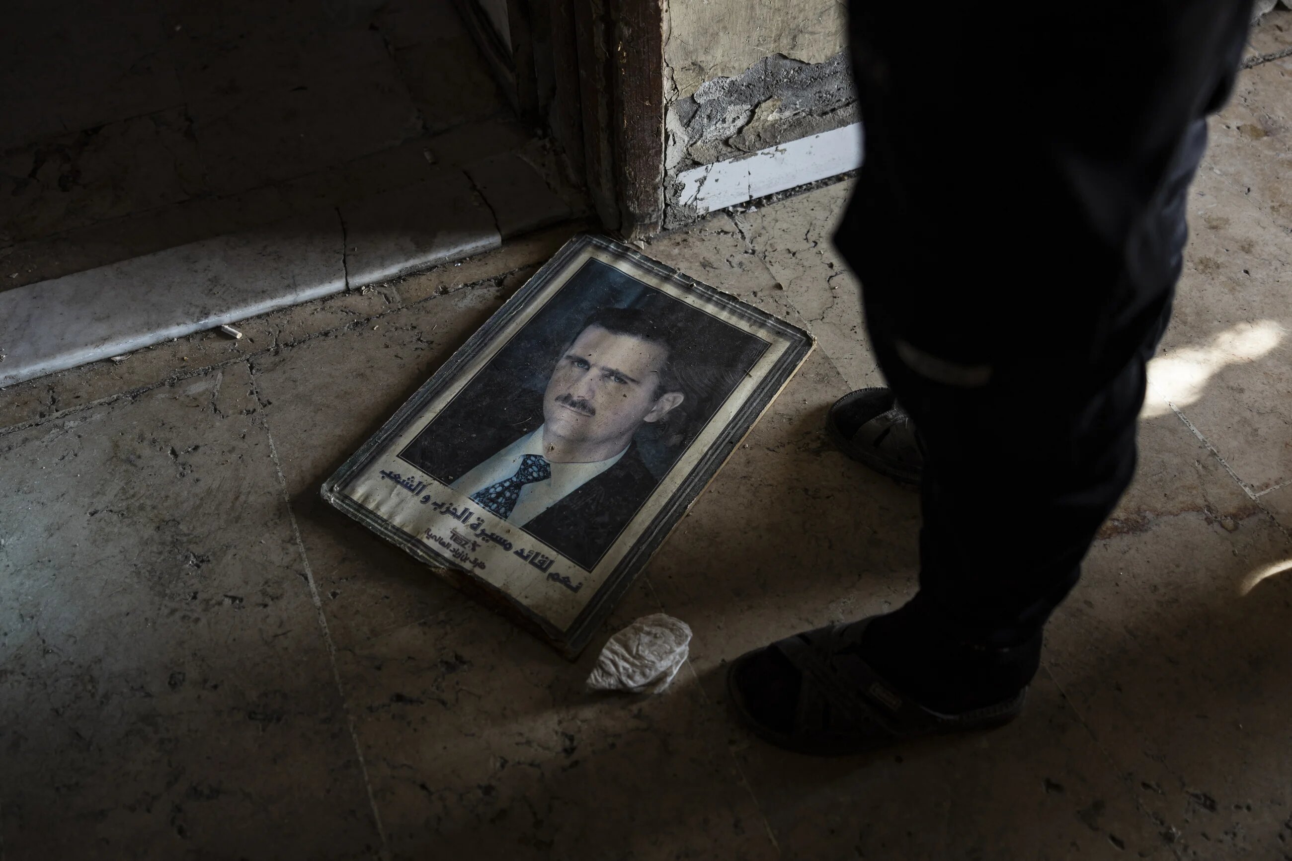 A man stands next to a portrait of toppled Syrian President Bashar al-Assad in the capital Damascus on 20 December 2024 (Sameer al-Doumy/AFP)