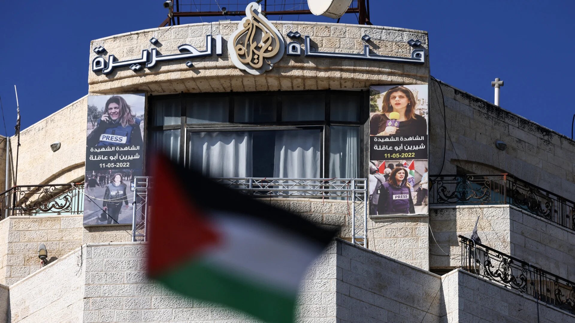Pictures of slain Palestinian journalist Shireen Abu Akleh hang across the facade of the building housing the Doha-based Al Jazeera TV channel in Ramallah, in the occupied West Bank, on 2 January 2025 (Jaafar Ashtiyeh/AFP)