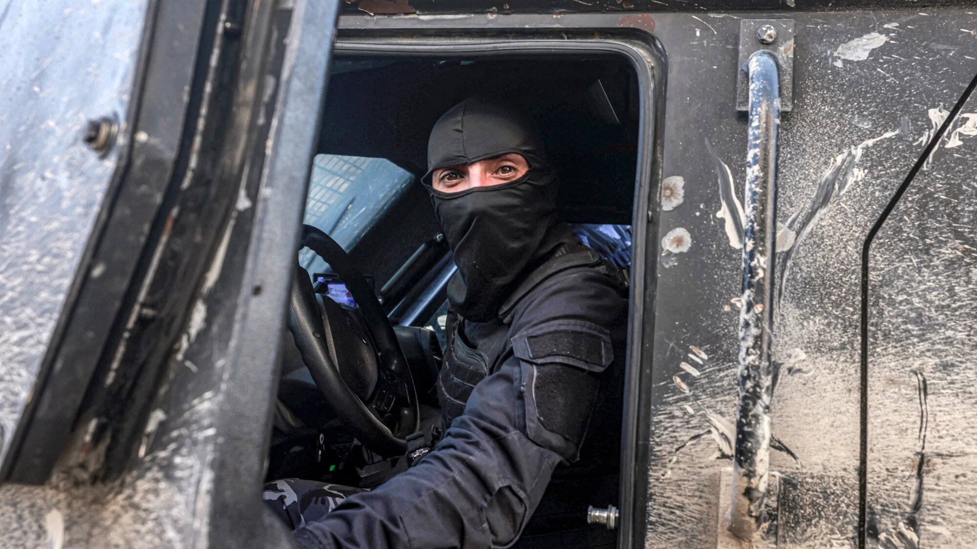 A Palestinian Authority security officer watches from inside an armoured vehicle as forces deploy in the Jenin camp for Palestinian refugees in the occupied West Bank on 18 January 2025 (AFP/Jaafar Ashtiyeh)