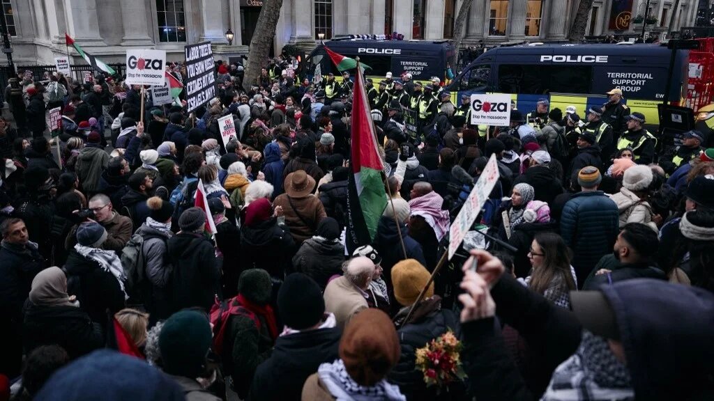 Protesters holding placards and flags face a line of police at Trafalgar Square in central London at a National demonstration for Palestine, on January 18, 2025 (AFP)
