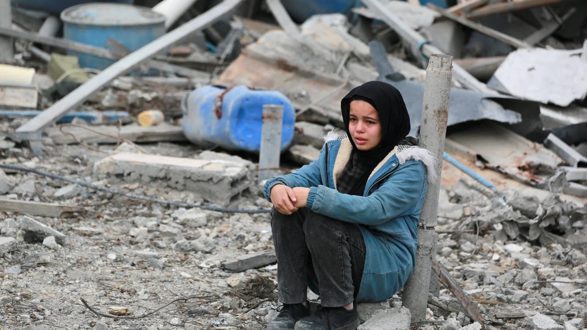 A Palestinian child cries as she sits amid building rubble in a ruined neighbourhood of Gaza's southern city of Rafah on 22 January 2025, as residents return following a ceasefire deal (Bashar Taleb/AFP)