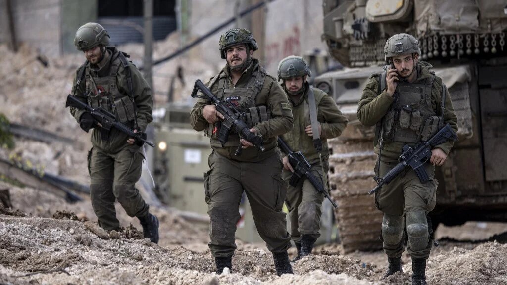 Israeli soldiers walk behind a tank in the Jenin camp for Palestinian refugees, in the occupied West Bank during a military operation on February 24, 2025. (AFP)