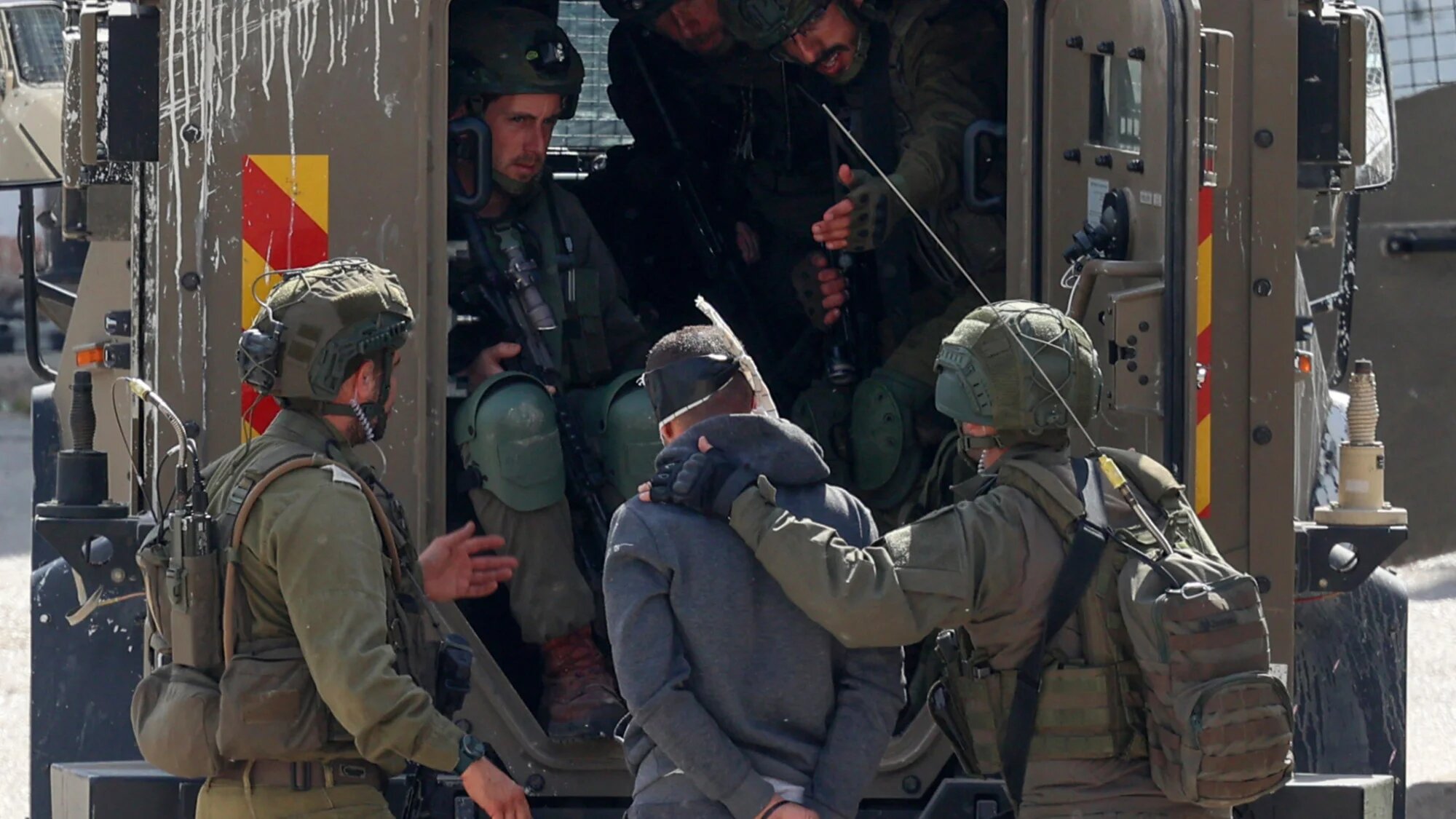 Israeli soldiers detain a blindfolded man during a raid on the Askar camp for Palestinian refugees east of Nablus in the occupied West Bank on 18 March 2025 (AFP/Zain Jaafar)
