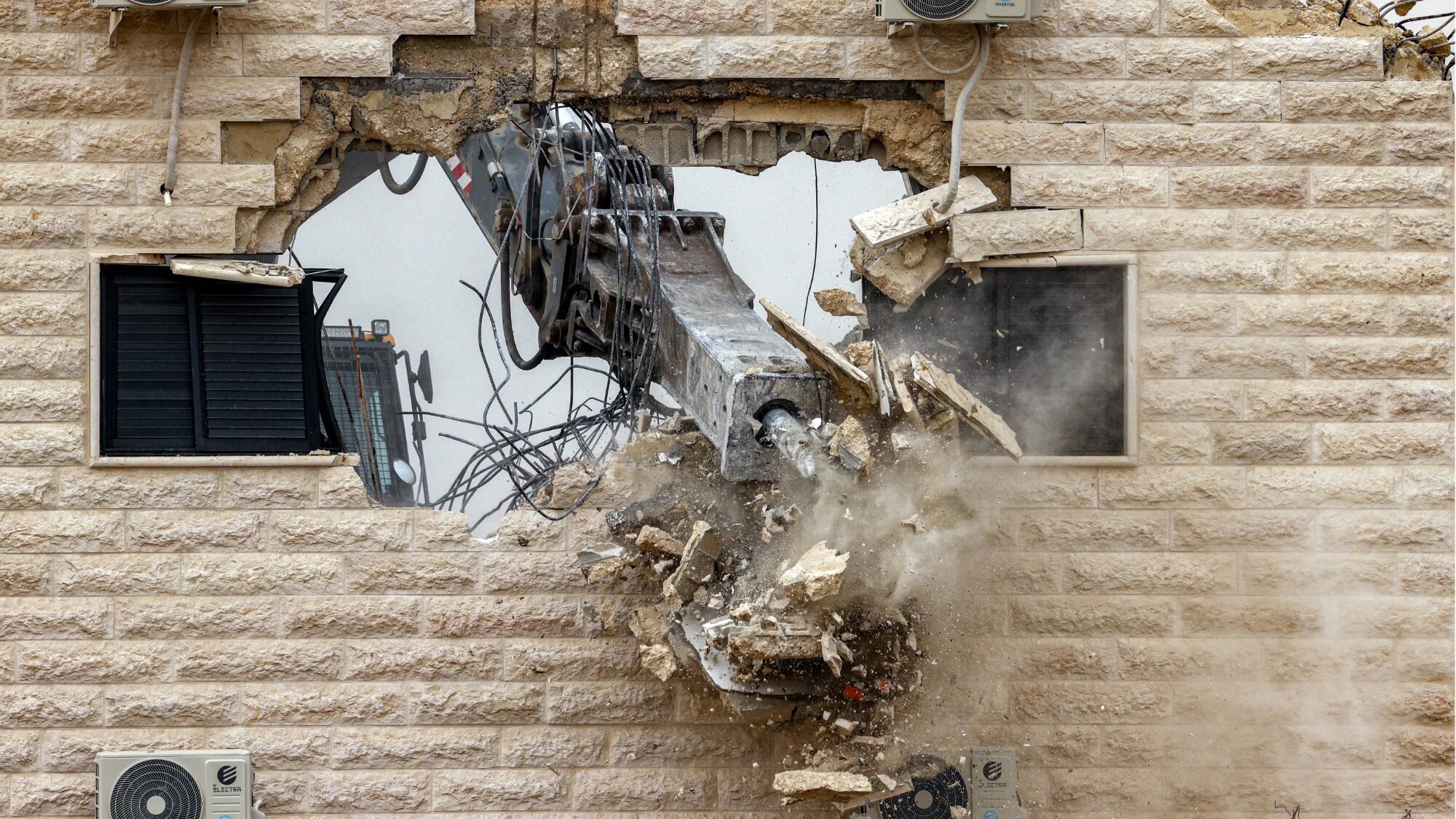 An Israeli excavator fitted with a breaker tool demolishes a Palestinian building constructed without a permit, in the village of al-Samua, south of Hebron in the occupied West Bank, on 8 April 2025 (AFP/Hazem Bader)