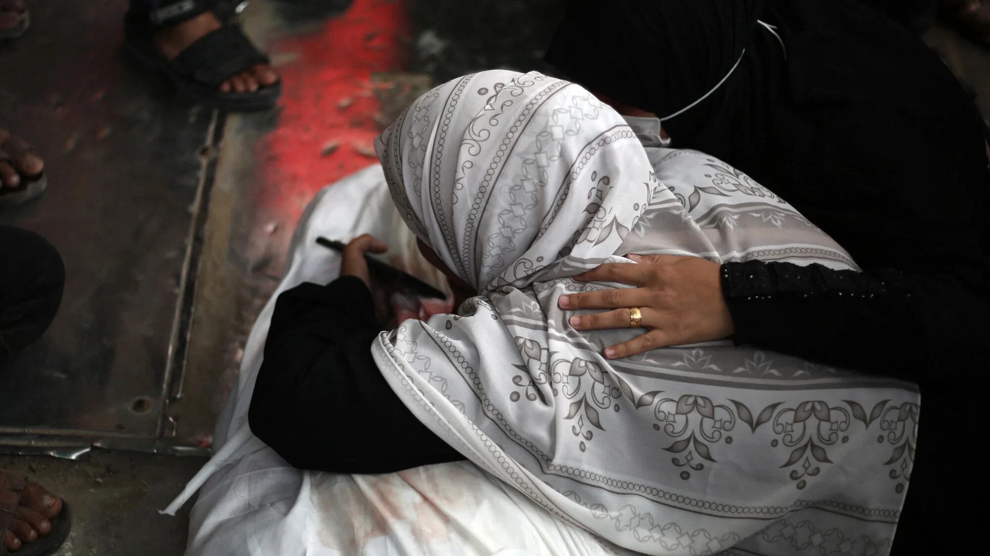 A Palestinian woman mourns over a shrouded body at al-Aqsa Martyrs hospital, Deir el-Balah, Gaza, on 13 April 2025 (AFP/Eyad Baba)