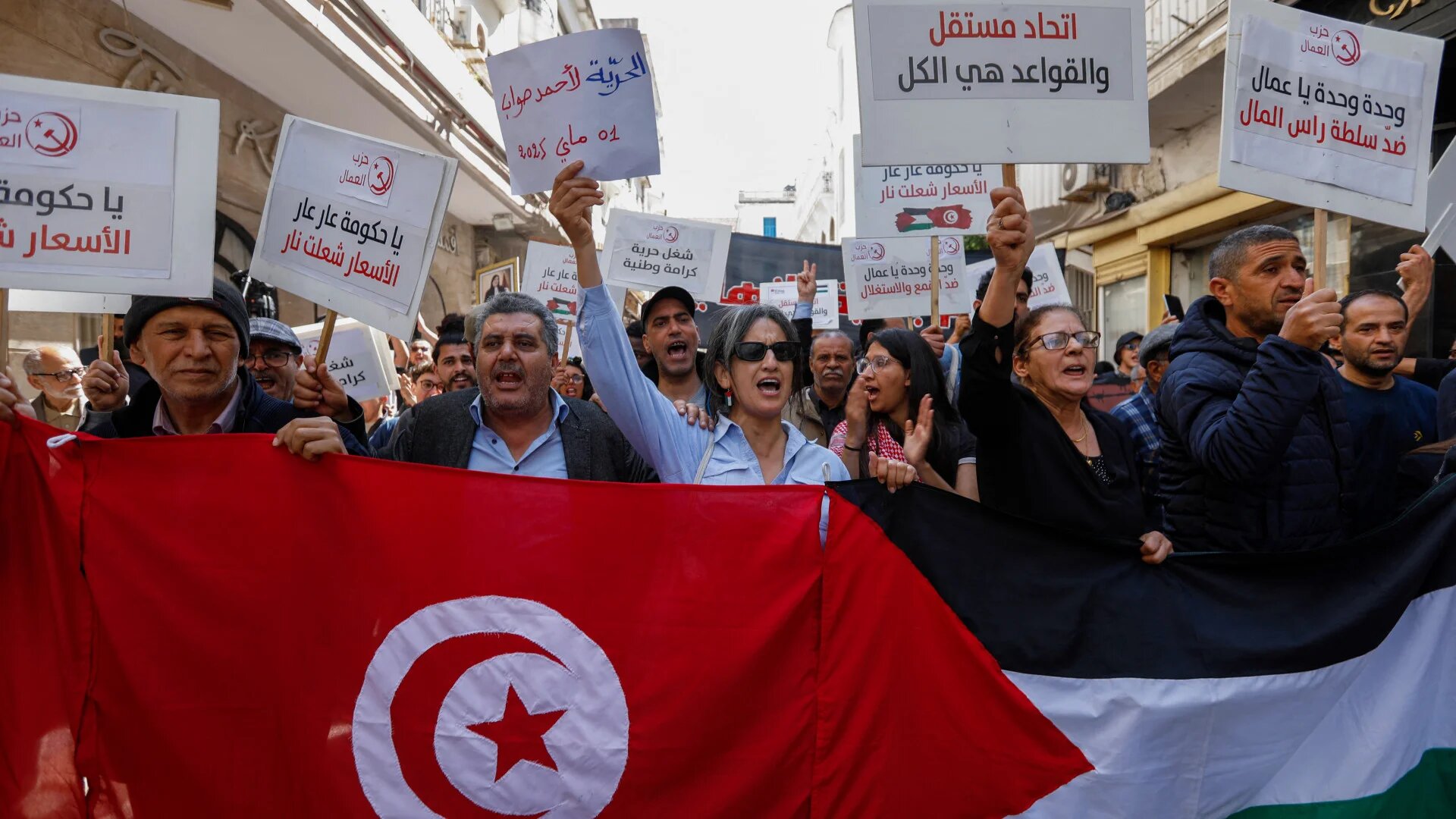 Tunisians wave national and Palestinian flags during a May Day protest in Tunis against President Kais Saied and in support of jailed opposition figures, on 1 May 2025 (Mohamed Khalil/AFP)