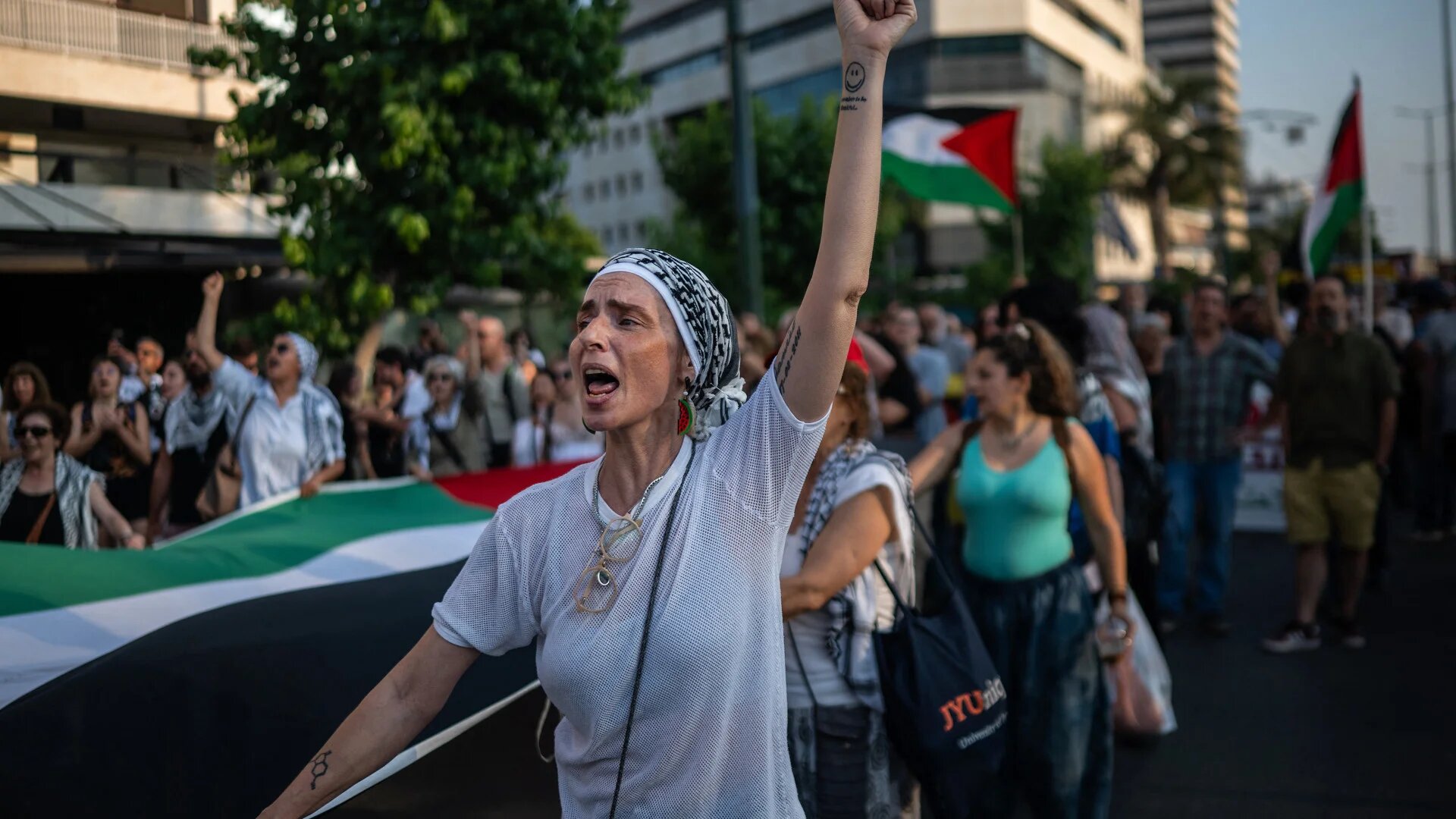 A protester raises her fist and holds a giant Palestinian flag outside the Israeli embassy during a demonstration in support of Palestine, in Athens, Greece on 9 June 2025 (Angelos Tzortzinis/AFP)