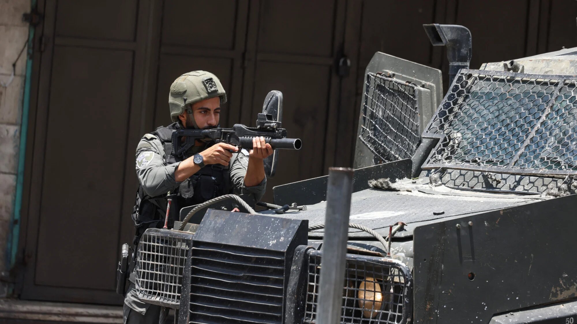 An Israeli soldier takes aim as he fires tear gas at Palestinians during a raid in the Old City of Nablus city in the occupied West Bank on 10 June 2025 (AFP/Jaafar Ashtiyeh)