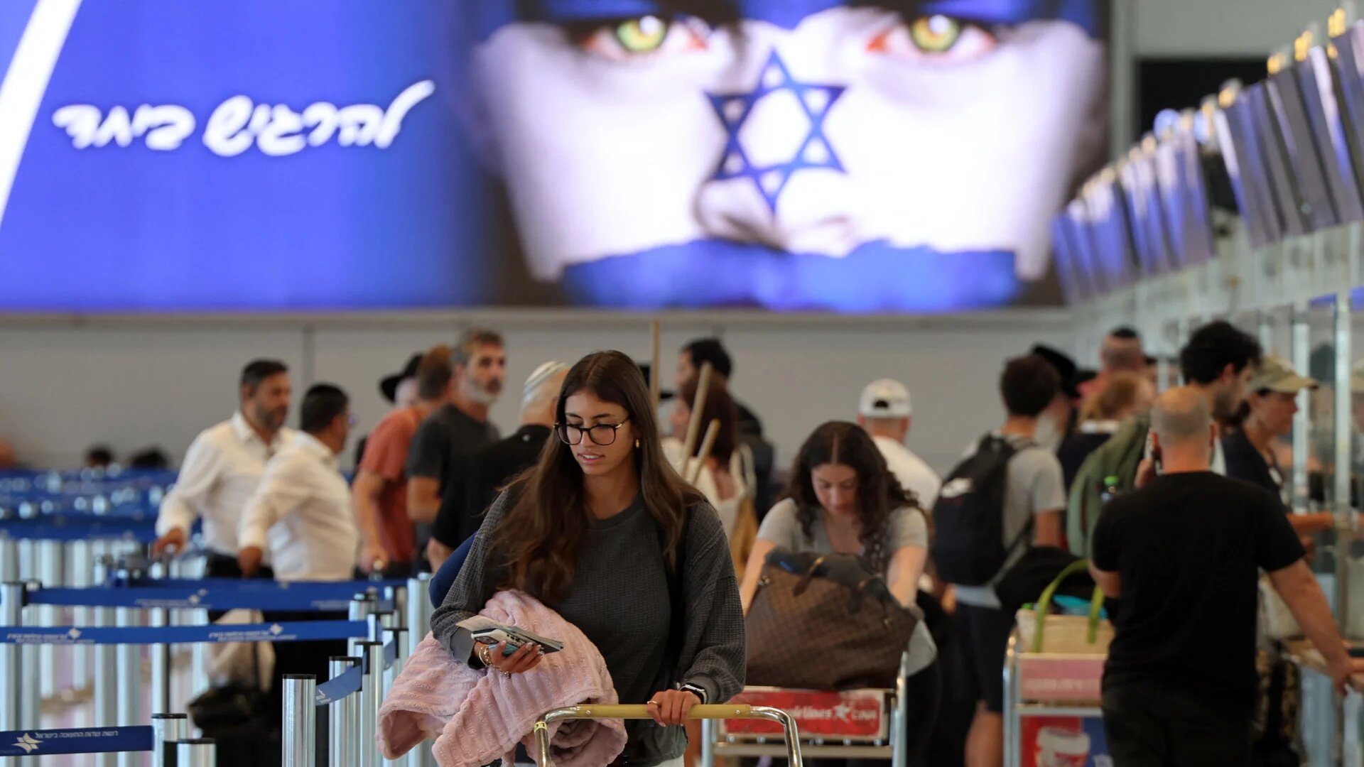 Passengers check in their luggage at the desk at Israel's central Ben Gurion Airport on 25 June 2025 (Jack Guez/AFP)