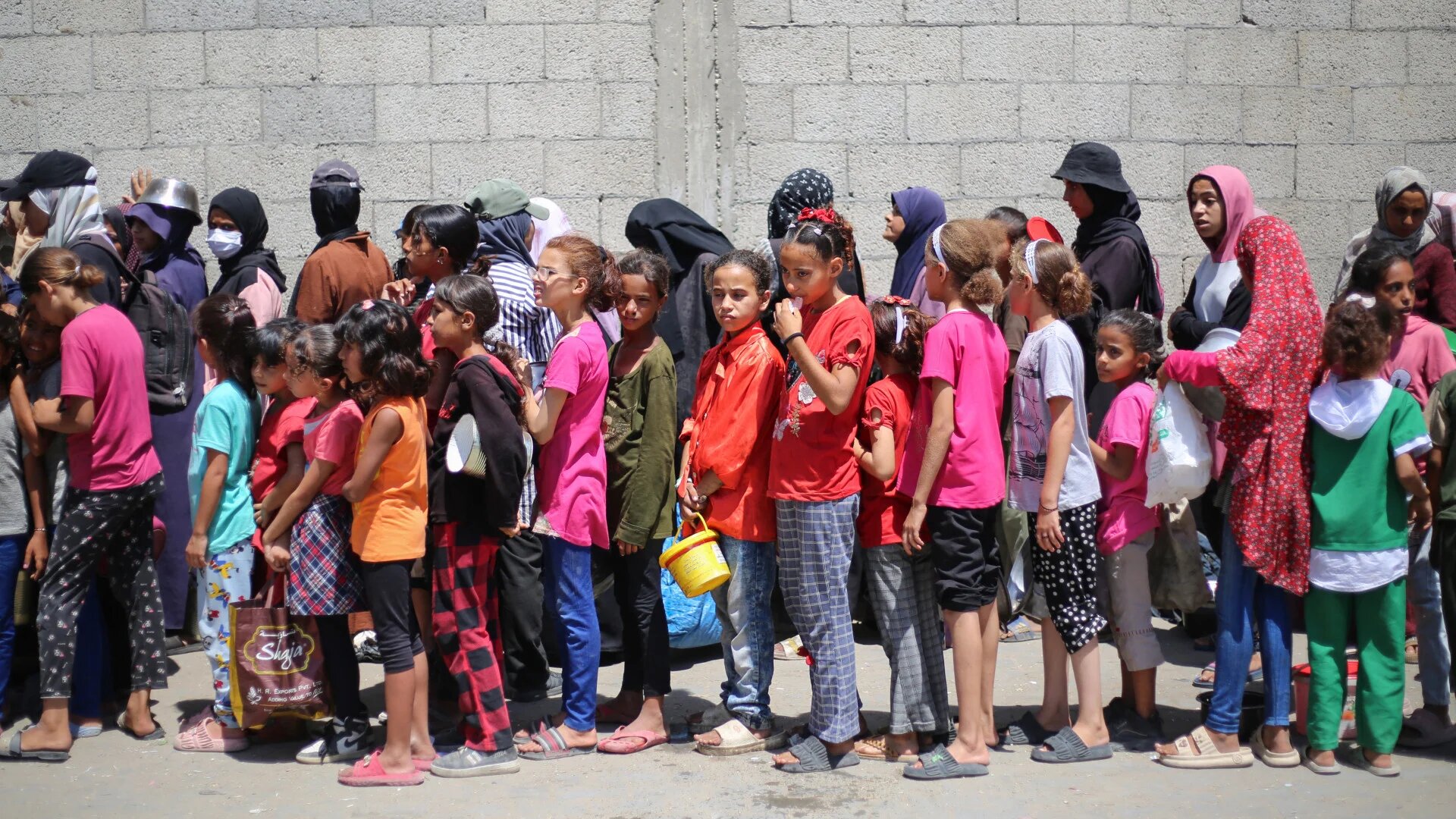 Palestinian children queue for hot food distributed by a charity kitchen at the Nuseirat refugee camp in central Gaza, 15 July 2025 (Eyad Baba/AFP)