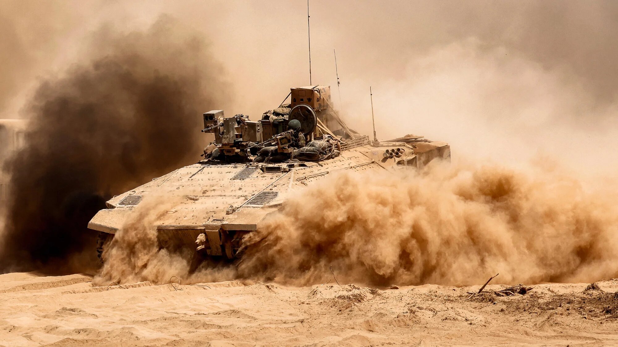 An Israeli army infantry fighting vehicle (IFV) leaves a cloud of dust as it moves at a position along the boundary with the Gaza Strip and southern Israel on 29 July 2025 (AFP/Jack Guez)