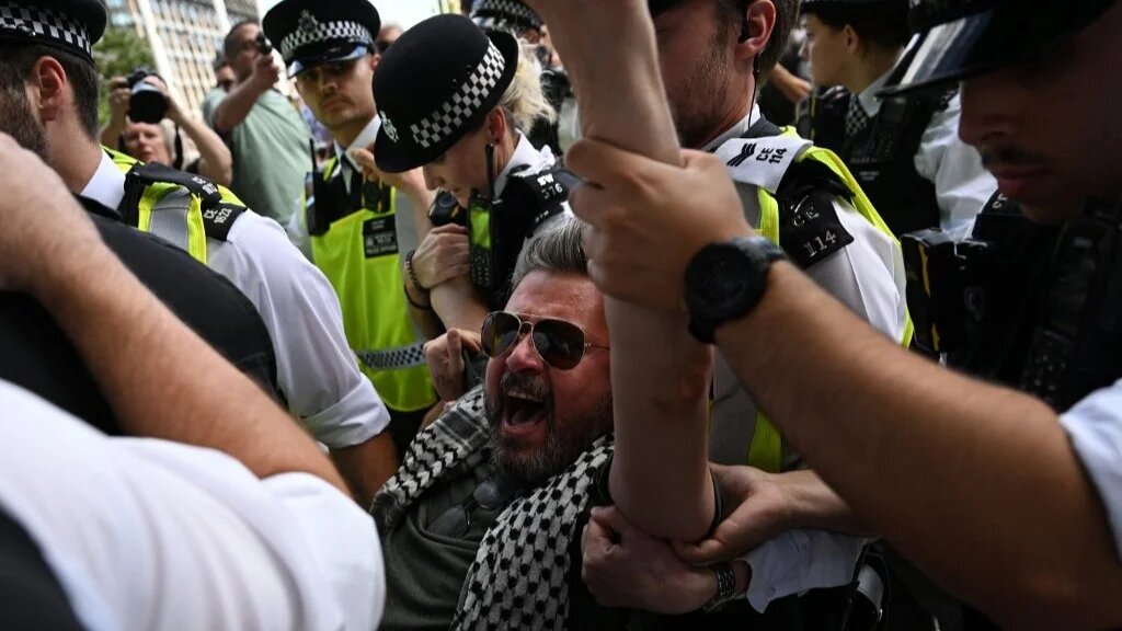 Police officers make an arrest at a demonstration against the proscription of Palestine Action in Parliament Square, central London, on 9 August 2025 (AFP)