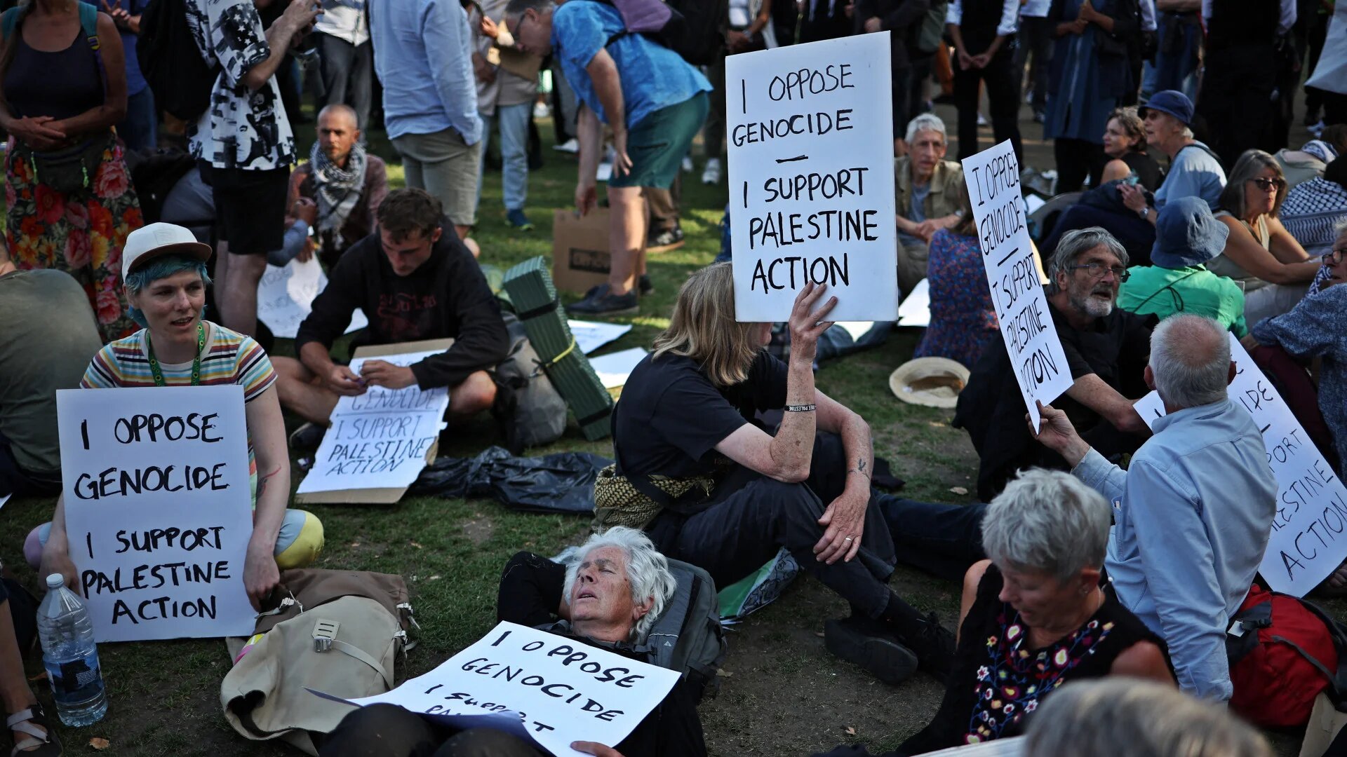 Protesters sit with placards backing Palestine Action at a "Lift the Ban" demonstration in Parliament Square, central London, on 9 August 2025, after the group was proscribed under the Terrorism Act 2000 (Henry Nicholls/AFP)