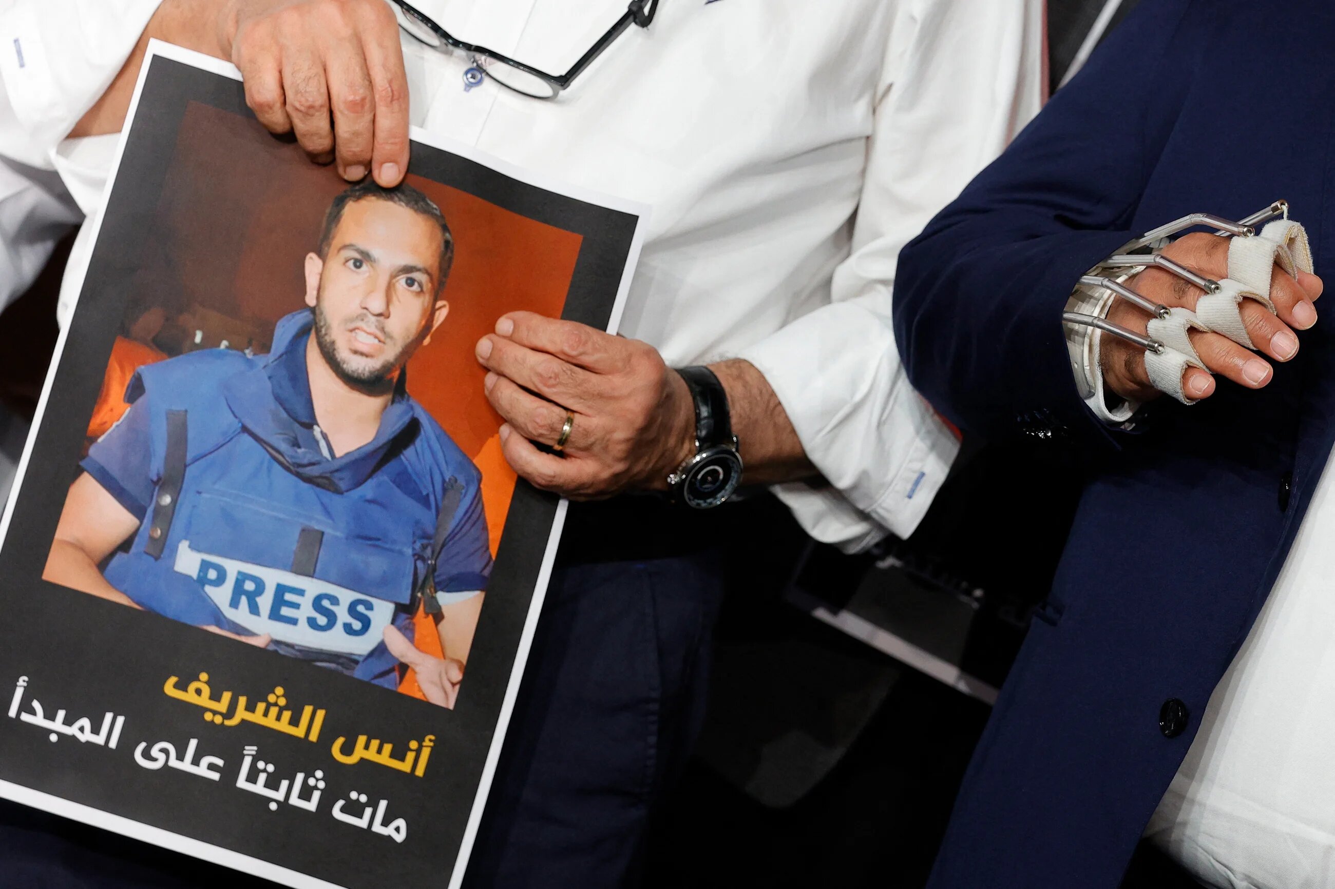Wael Al-Dahdouh, Al Jazeera's bureau chief in Gaza, stands next to Al Jazeera anchor Mohamed Krichen holding the portrait of Anas al-Sharif during a moment of silence to honor Anas and four other colleagues (Karim Jaafar/AFP)