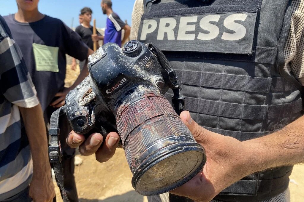 A journalist holds the blood-covered camera belonging Mariam Dagga, a Palestinian photojournalist killed in an Israeli strike on Nasser hospital in Khan Yunis in the southern Gaza Strip, during her funeral on 25 August, 2025. (AFP)