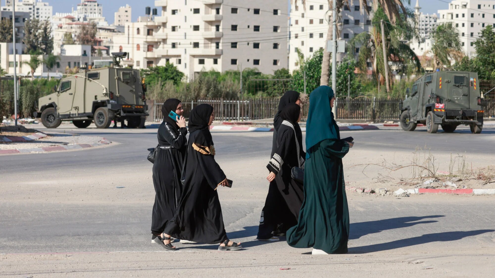 Palestinian women walk past Israeli troops in Tulkarem in the occupied West Bank on 11 September 2025 (Jaafar Ashtiyeh/AFP)