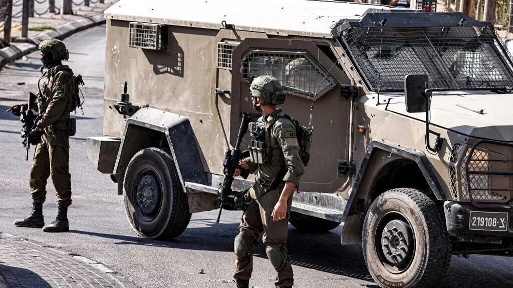 Israeli army soldiers and vehicles take position at the entrance of al-Amari refugee camp in the occupied West Bank city of Ramallah during an army raid there on September 14, 2025
