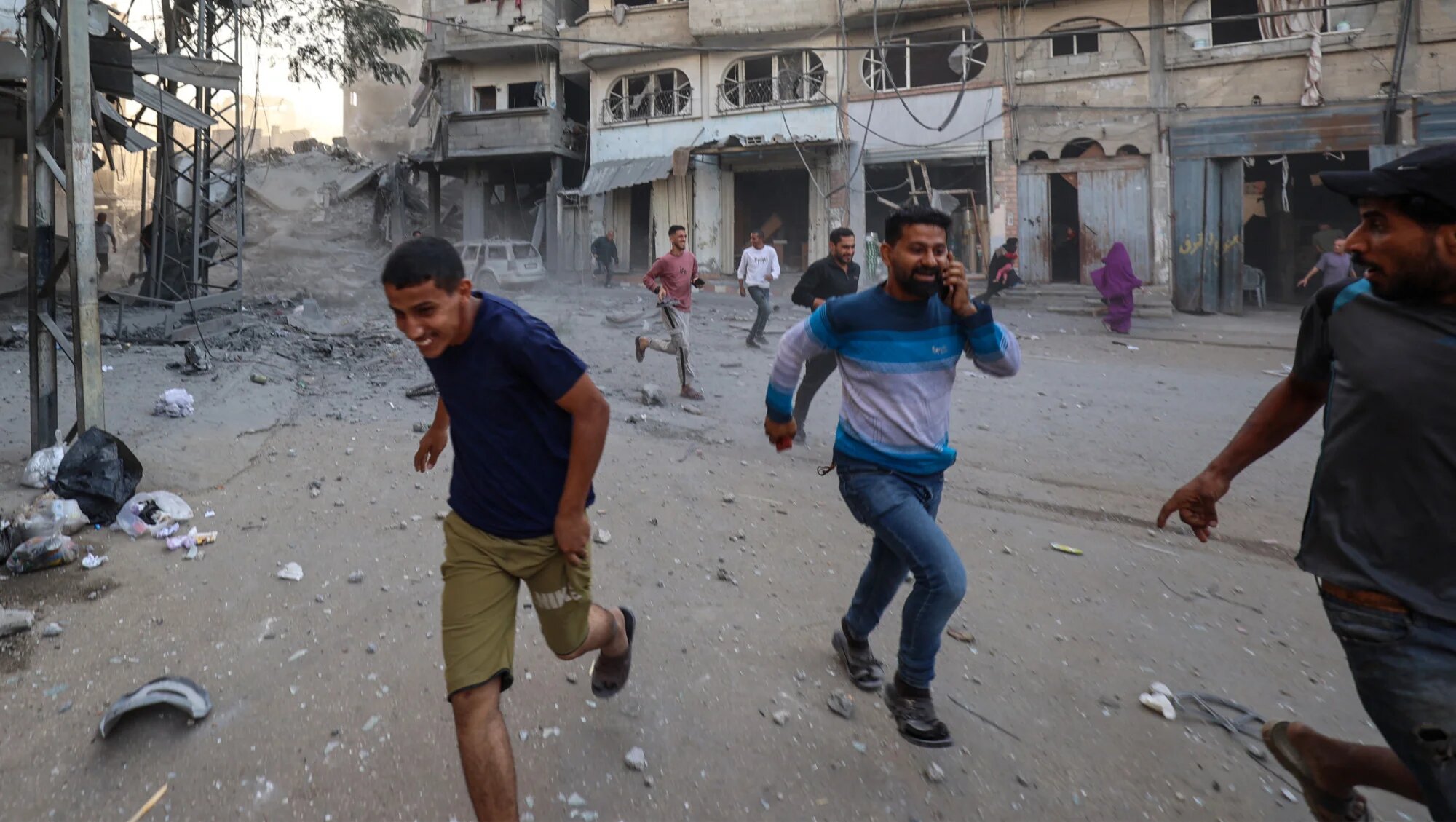 People run for cover following an Israeli strike in the Bureij camp for Palestinian refugees in the central Gaza Strip on 19 October 2025 (AFP/Eyad Baba)