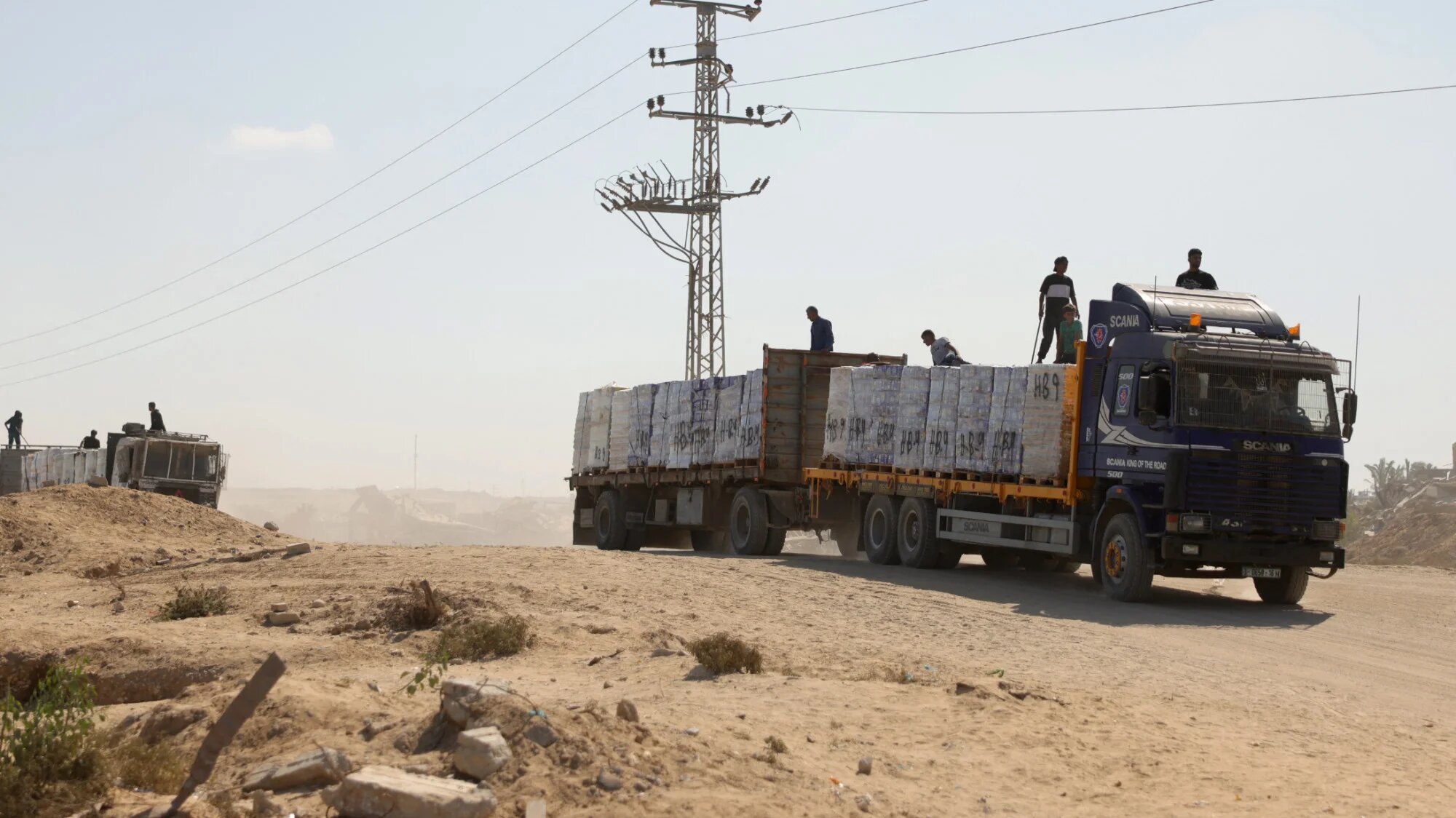 One of ten aid trucks drive along a dusty road after entering through the Kissufim crossing in southern Israel, towards Deir al-Balah, in the central Gaza Strip on 27 October 2025 (AFP/Bashar Taleb)