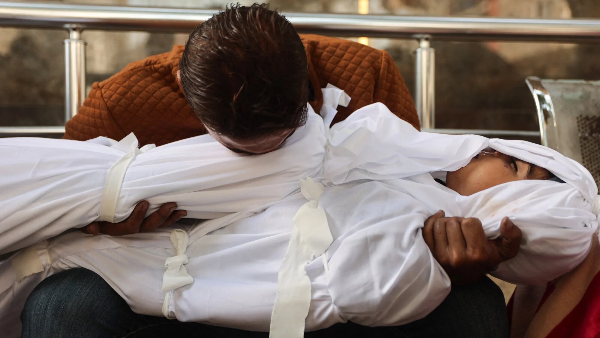 Palestinian Mahmud Shakshek mourns over the bodies of his children, Fadi (R) and Sarah, who were killed in overnight Israeli strikes, at the Al-Shifa Hospital in Gaza City on 29 October 2025 (AFP/Omar al-Qattaa)
