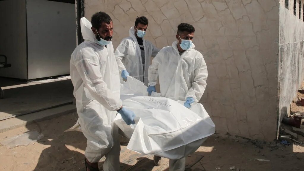 Employees at Nasser Medical Complex carry the body of a Palestinian prisoner who died in Israeli custody after Israel released his remains under a ceasefire agreement, in the southern Gaza Strip, on 31 October (AFP)