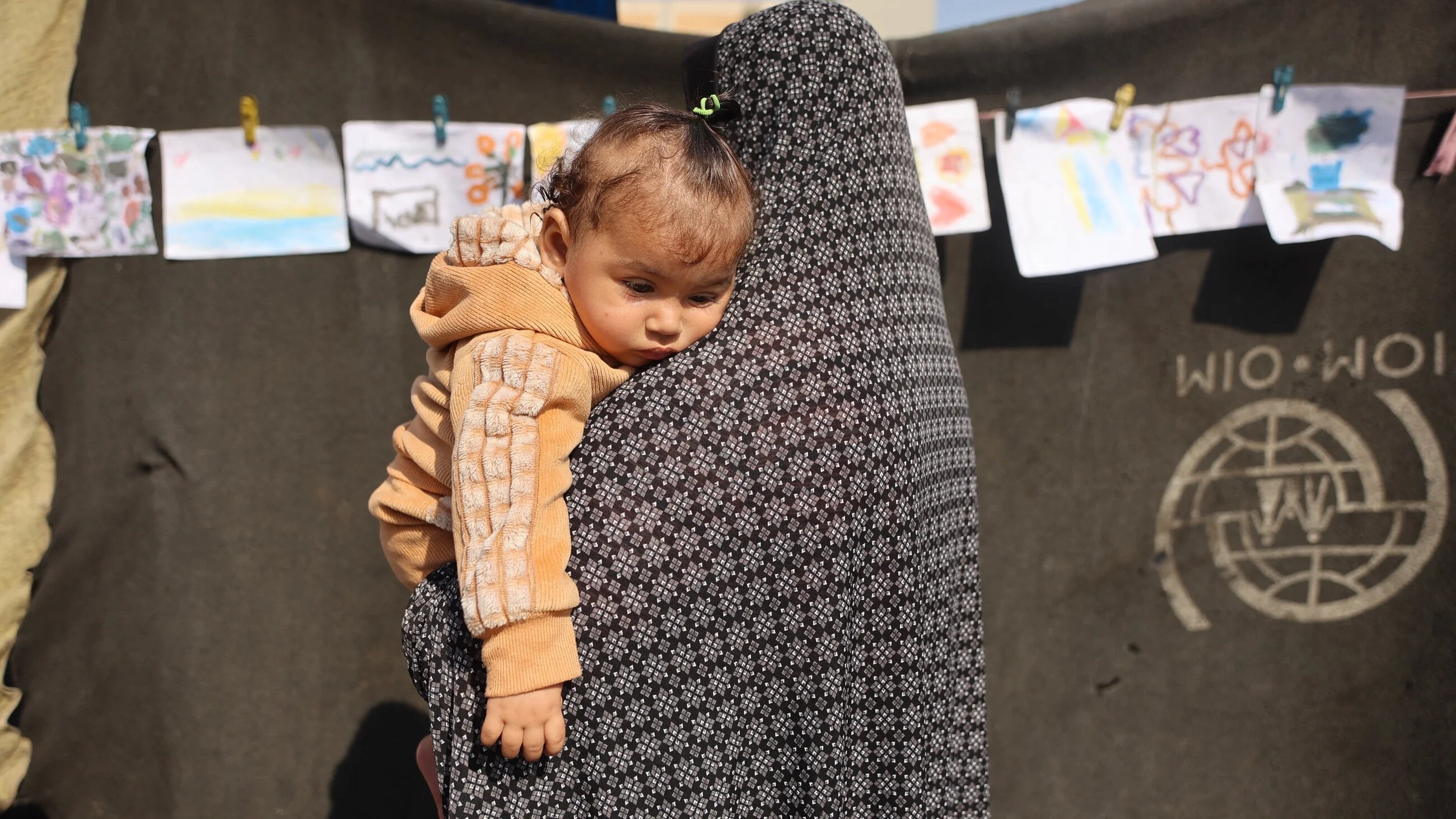 A woman carrying a child at a school-turned-shelter for displaced Palestinians in al-Rimal neighbourhood of Gaza City on 5 November, 2025 (AFP/Omar al-Qattaa)