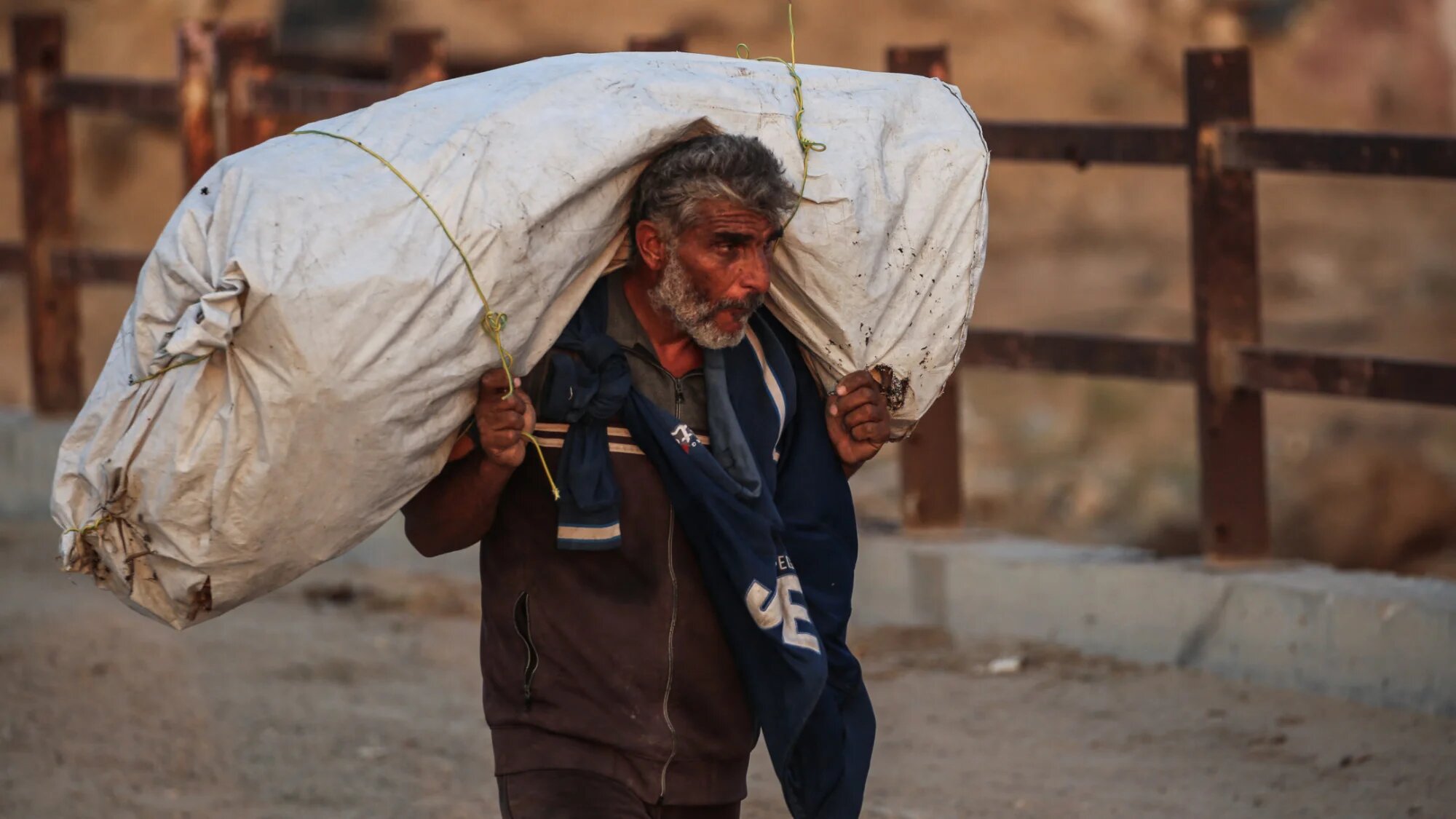 A Palestinian man carries his belongings along a bridge in Nuseirat, Gaza Strip on 11 November 2025 (AFP/Eyad Baba)