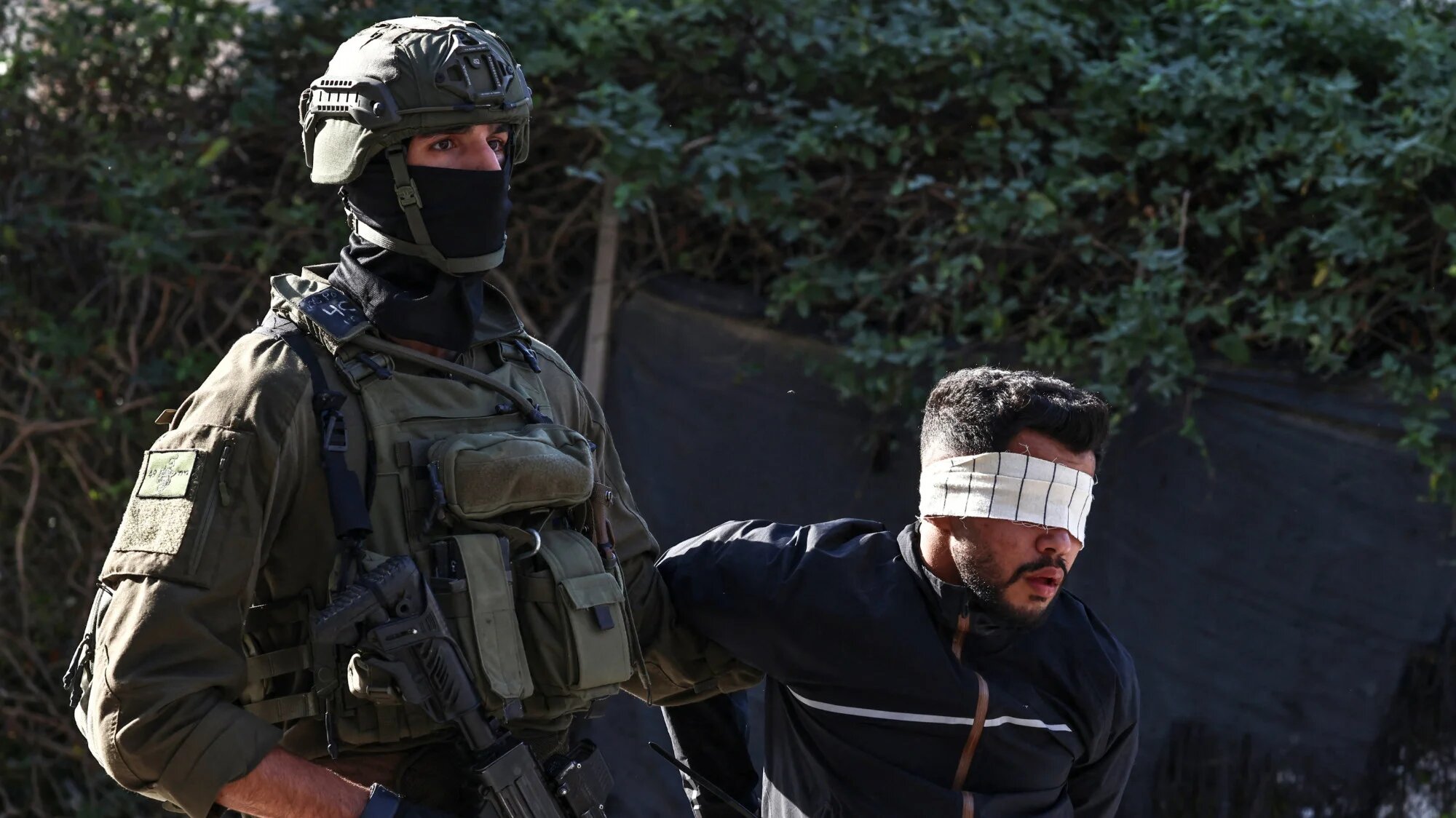 An Israeli soldier detains a Palestinian man during a military operation in the town of Qalqiya, in the occupied West Bank, on 4 December 2025 (AFP/Zain Jaafar)