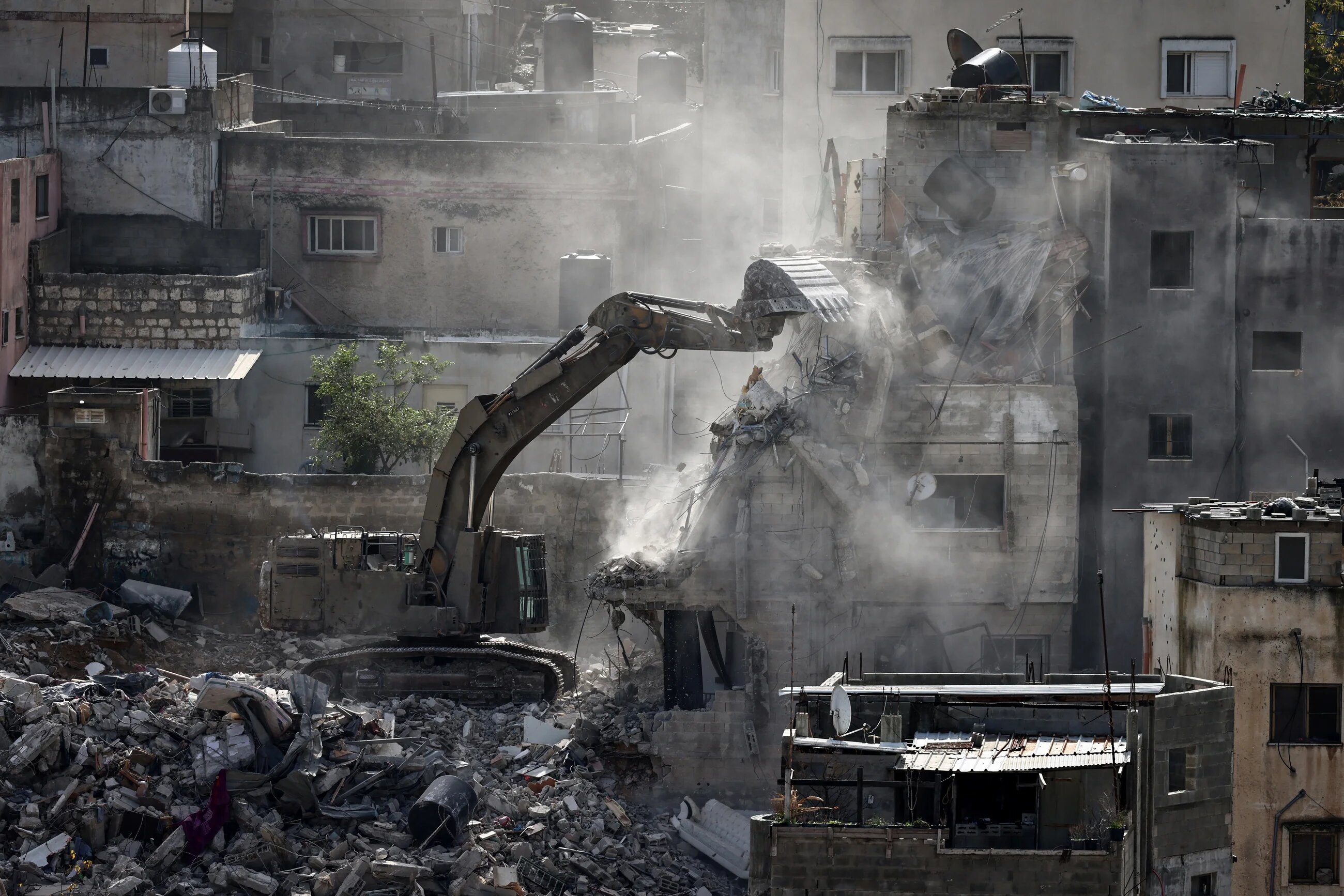 An Israeli military excavator tears down one of 25 residential buildings earmarked for demolition in the Nur Shams camp for Palestinian refugees near Tulkarem on 31 December 2025 (Zain Jaafar/AFP)