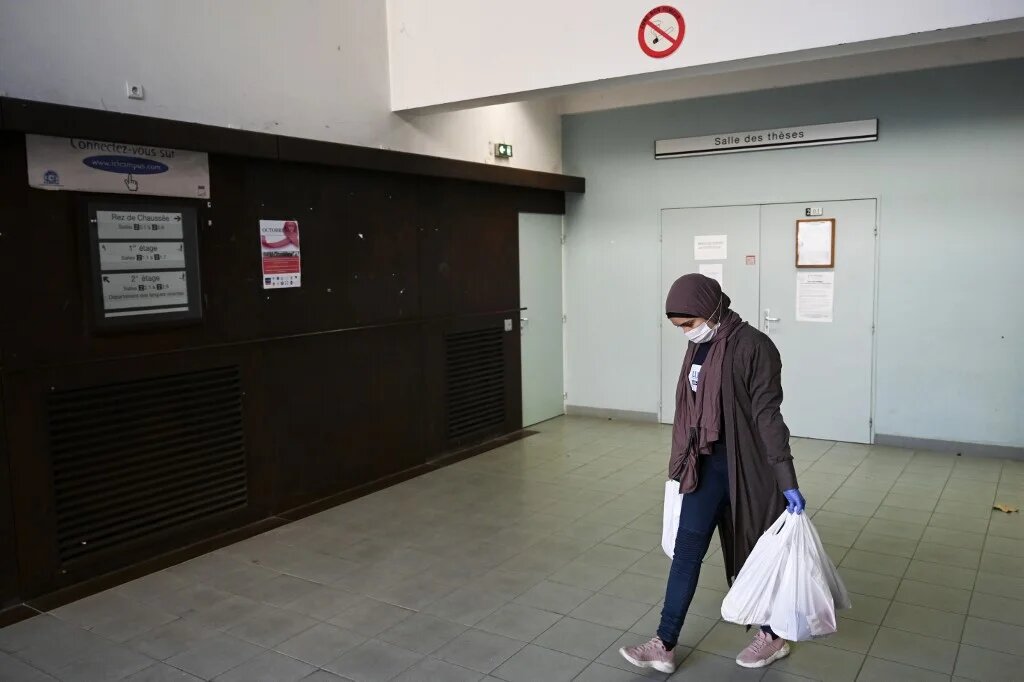 Une étudiante bénévole porte des sacs d’aide alimentaire sur un campus universitaire, le 17 novembre 2020 (AFP)