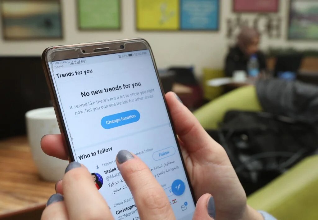 Zeina Shahla, a Syrian journalist, checks her twitter at a cafe in the capital Damascus on 1 March 2021. (AFP)