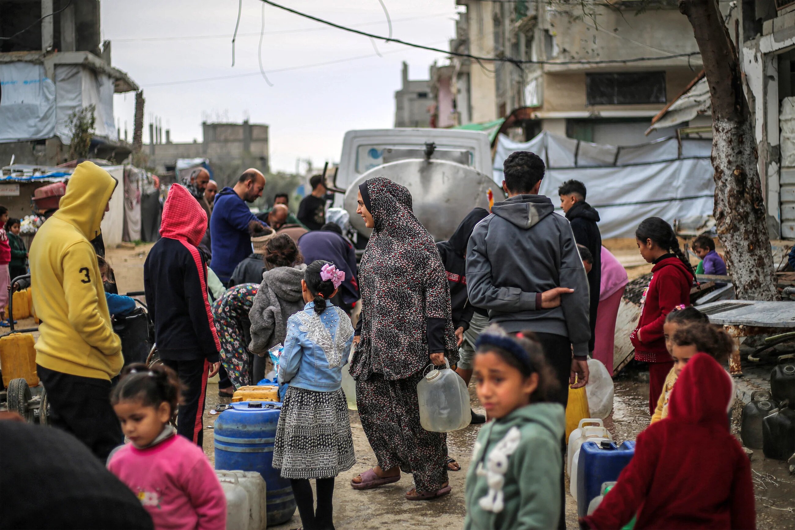 People queue to fill up containers with water in the Nuseirat camp for Palestinian refugees north of Deir al-Balah (Eyad Baba / AFP)