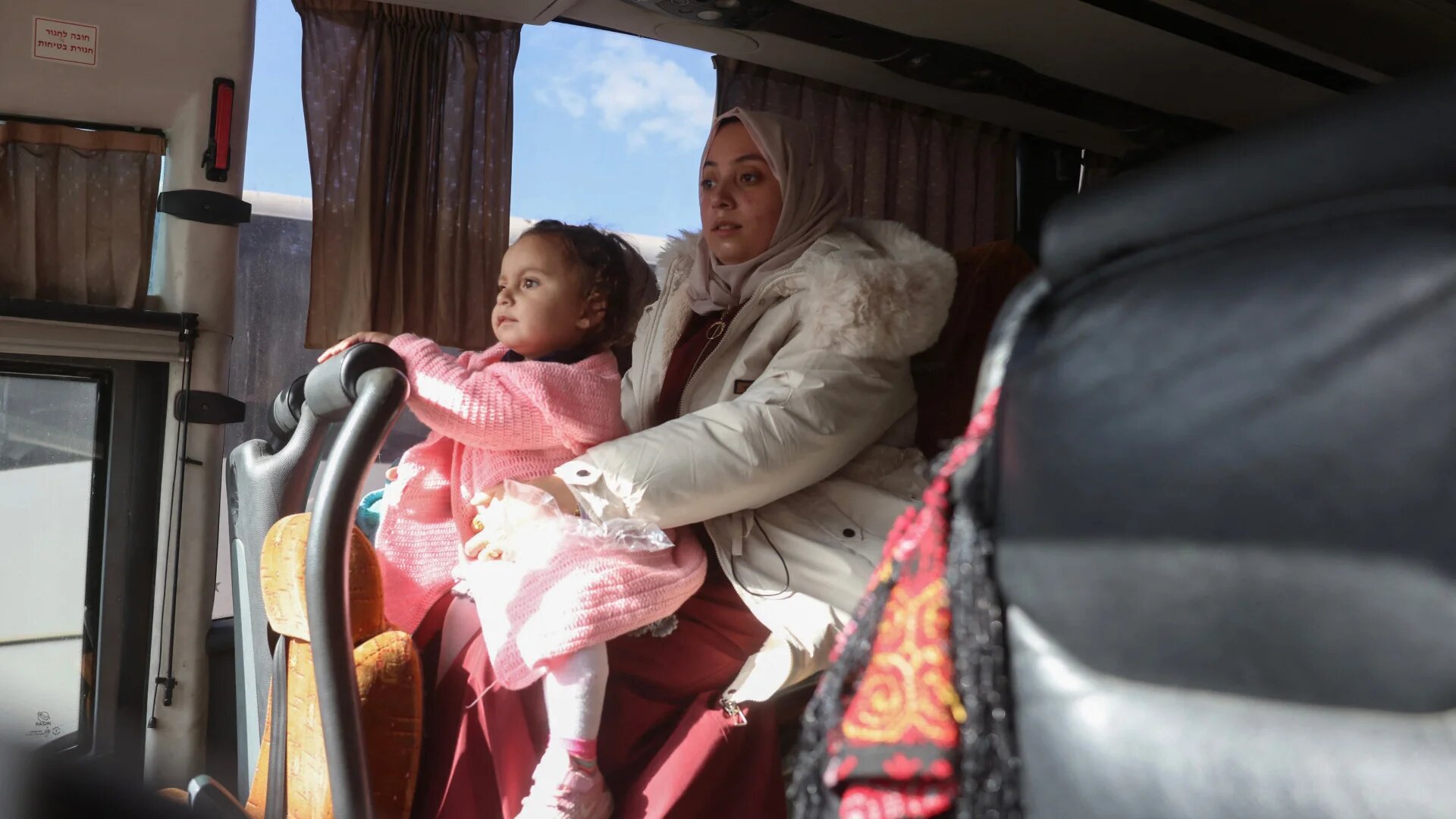 A woman holding a child sits on a bus as Palestinians evacuate Gaza through the Rafah crossing in Khan Younis, southern Gaza Strip, on 3 February 2026 (Bashar Taleb/AFP)