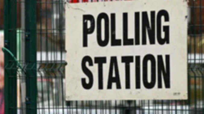 A person walks past a Polling Station sign in Levenshulme, Greater Manchester on February 26, 2026, to cast their ballot in the crucial Gorton and Denton by-election.