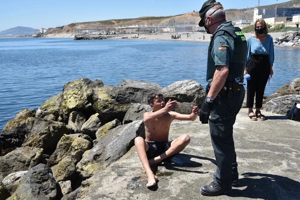 Un membre de la Guardia Civil (police à statut militaire) aide un migrant mineur à son arrivée par la nage à Ceuta, le 19 mai 2021 (AFP/Antonio Sempere)
