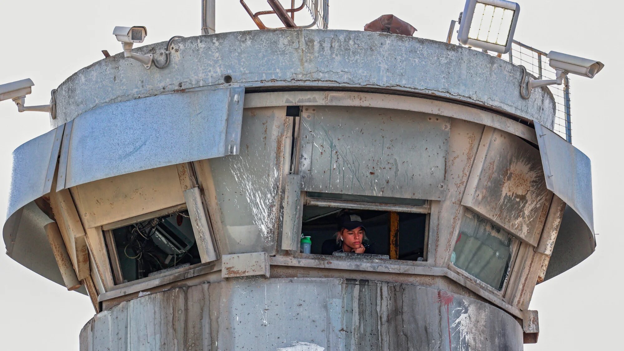 An Israeli soldier looks out from a watch tower at the Qalandia checkpoint between the occupied West Bank and Jerusalem, on 12 June 2021 (AFP/Abbas Momani)