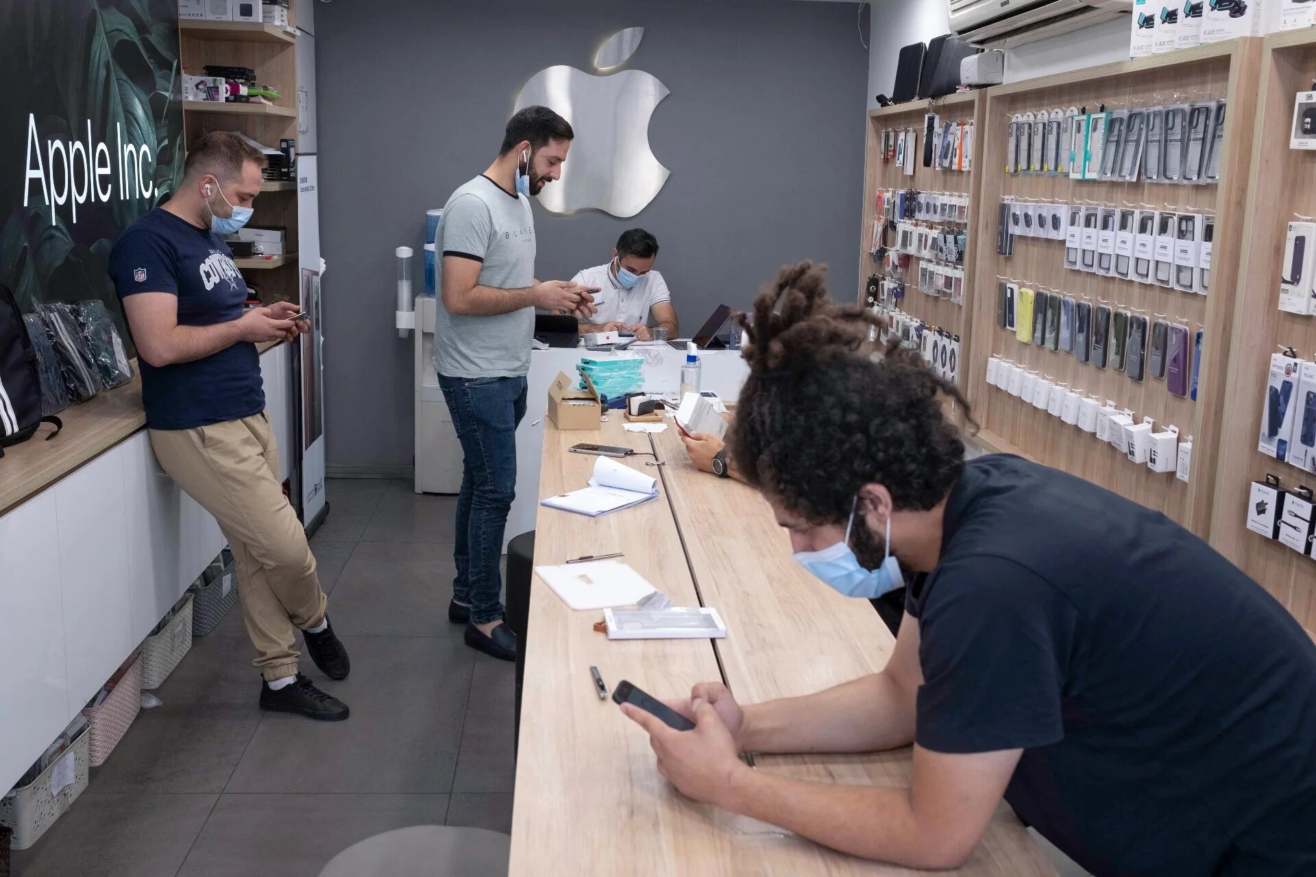 Iranian staff use their smartphones at a shop in northern Tehran on 19 June, 2021 (AFP)