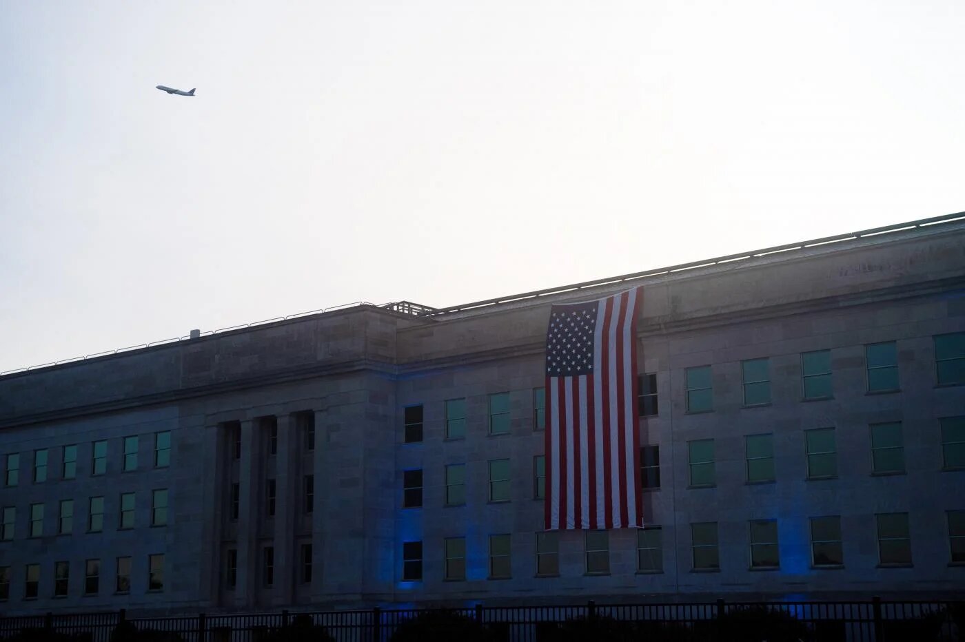 Un drapeau américain recouvre la façade du Pentagone, à Washington D.C., pour commémorer le 20e anniversaire des attentats du 11-Septembre, tandis qu’un avion passe dans le ciel, le 11 septembre 2021 (AFP)