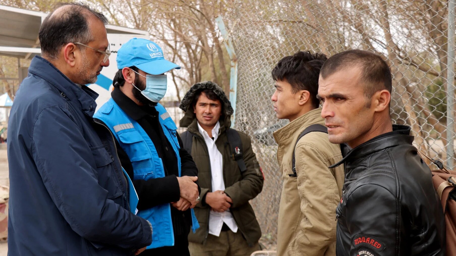 Arafat Jamal (left), representative of the United Nations High Commissioner for Refugees (UNHCR) in Afghanistan, speaks with Afghan nationals upon their arrival from Iran amid the Middle East war.