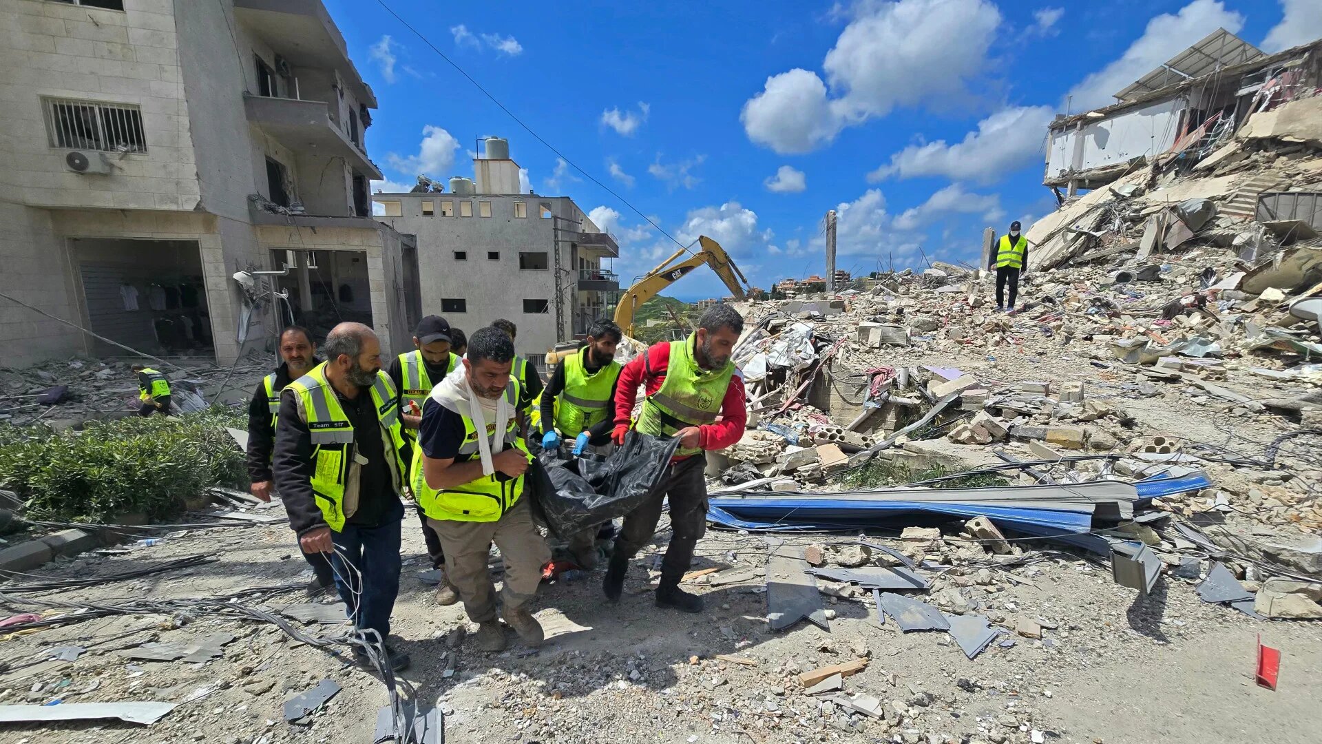 First responders carry a body from the rubble of buildings destroyed in an Israeli strike in Qana, southern Lebanon, on 12 April 2026 (Kawnat Haju/AFP)