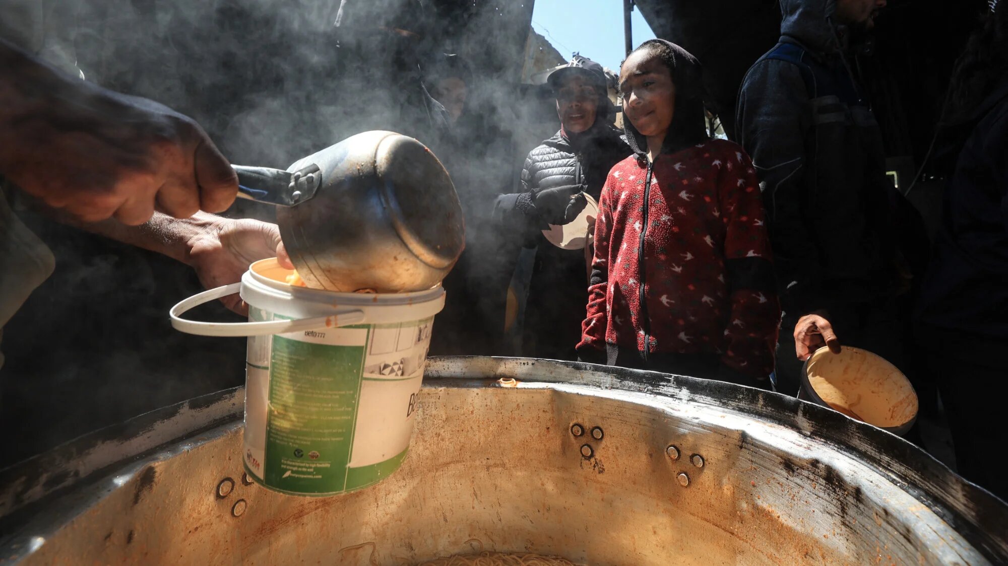 Displaced Palestinian children receive food from a charity kitchen at the Nuseirat refugee camp in the central Gaza Strip on 13 April 2026 (AFP/Eyad Baba)