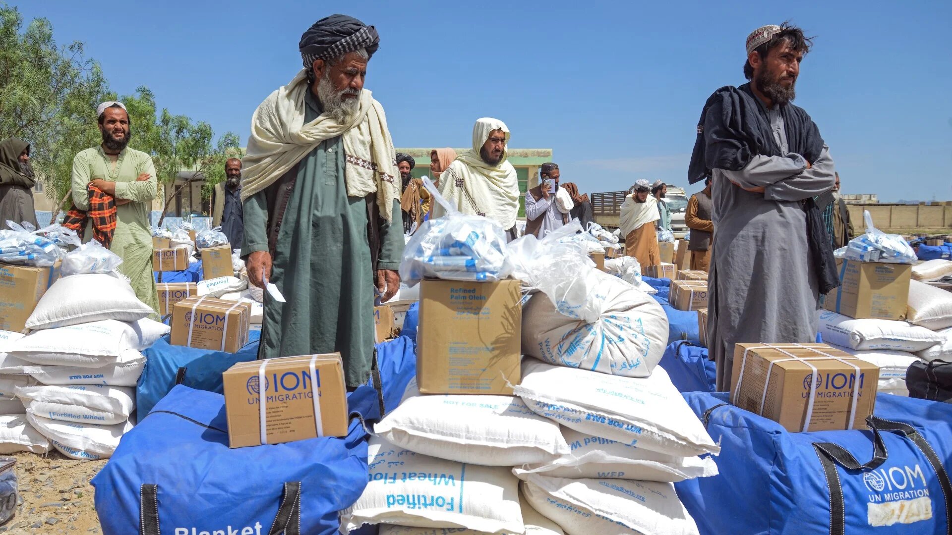 Afghan flood-affected men stand next to food aid and household kits, distributed by the UN World Food Programme in the Daman district of Afghanistan’s Kandahar province, 13 April, 2026.