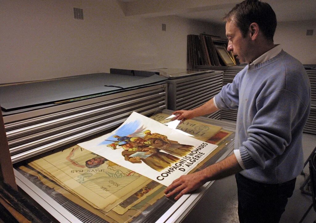 Un homme regarde des affiches datant de la guerre d’Algérie dans une salle du Service historique de l’Armée de terre (SHAT), dans le fort de Vincennes, le 29 octobre 2001 (AFP)
