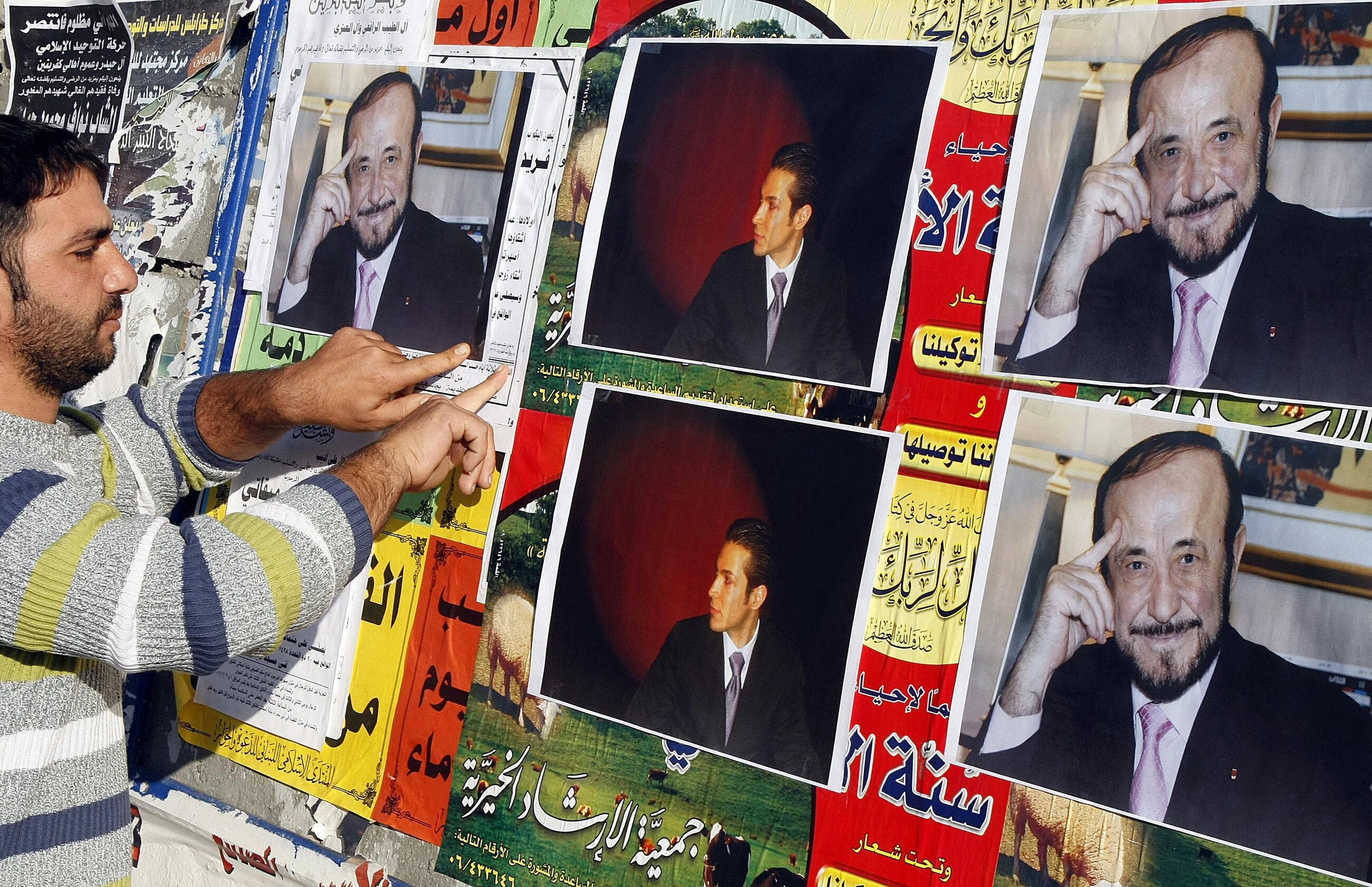 Archive image: A member of the Alawite community pastes posters of Syrian opposition leader Rifaat al-Assad (R) and his son Ribal on a wall in the northern Lebanese city of Tripoli, 06 December 2007