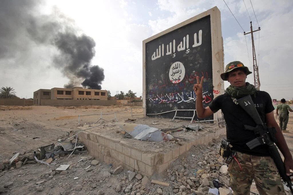 Un combattant du Hachd al-Chaabi devant le drapeau du groupe État islamique à al-Qaim, à l’ouest de l’Irak, le 3 novembre 2017 (AFP/Ahmad al-Rubaye)