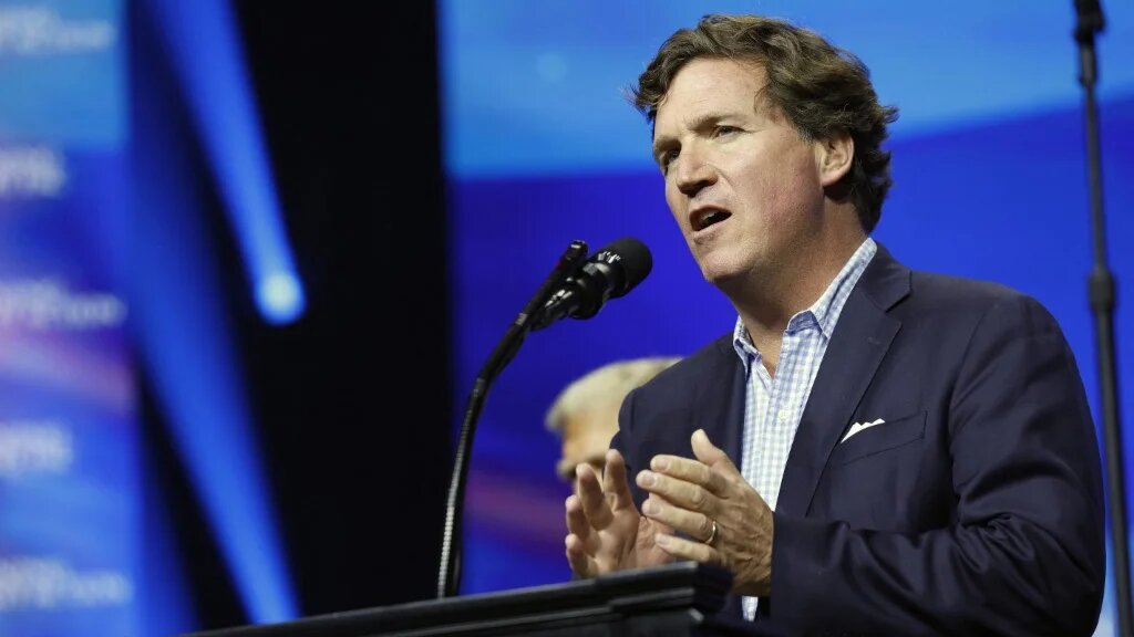 Tucker Carlson speaks at a Turning Point Action rally for Donald Trump at the Gas South Arena in Duluth, Georgia, on 23 October 2024 (AFP)